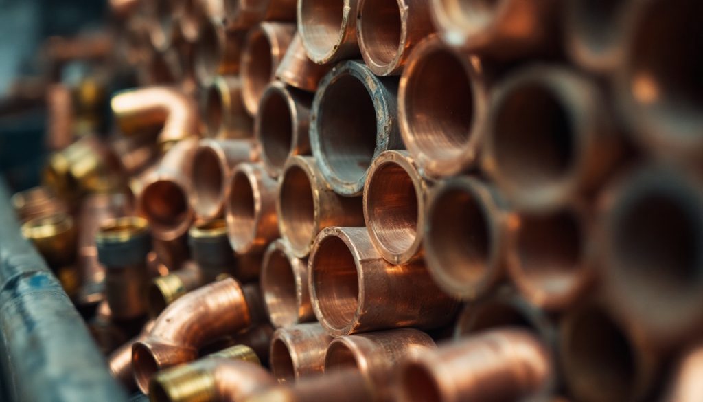 Close-up of stacked copper pipe ends and brass fittings in a supply house bin